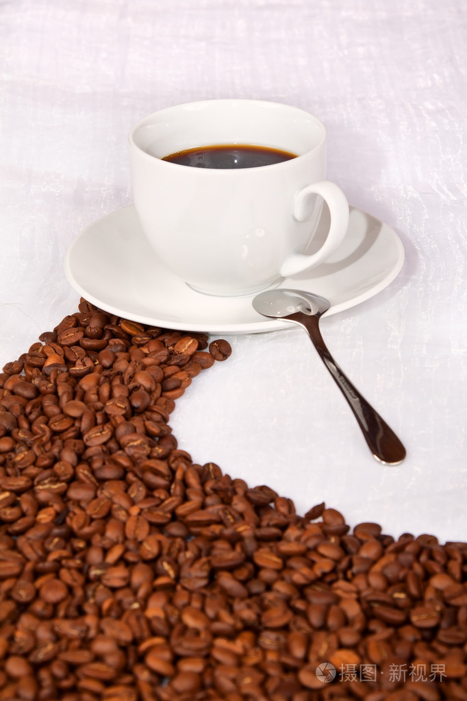 路径向一杯白咖啡的咖啡豆