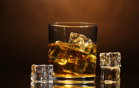 杯威士忌和棕色背景上冰