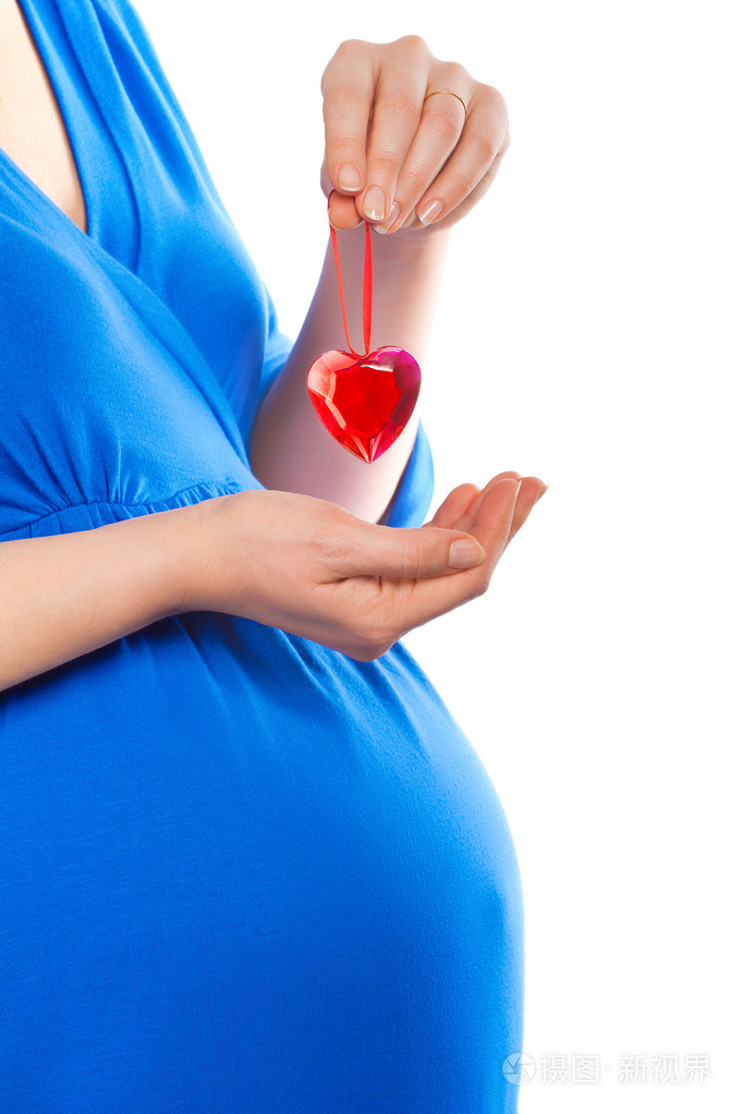 怀孕的女人在她的肚子特写拍摄握着的心