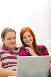 开心快乐年轻夫妇时间与便携式计算机