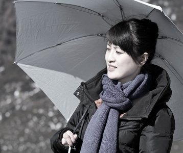 美丽的亚洲女孩举行反对太阳伞
