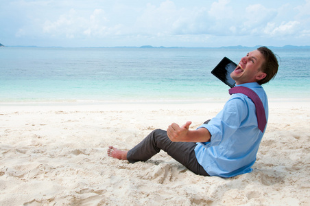 开心事业人坐在沙滩与平板电脑上工作