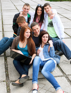组的男学生和女学生坐在一起在大街上的一台笔记本电脑