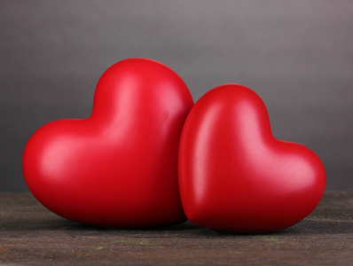 灰色背景上的木桌上的两个装饰红色心