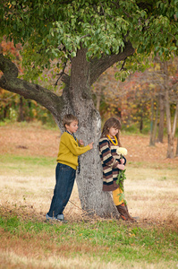 站在一棵树旁边的女孩与男孩