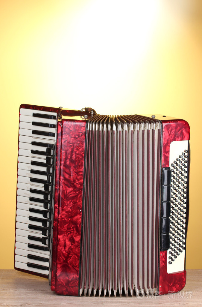 在黄色背景上的木桌上的复古手风琴