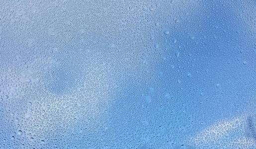 水滴在玻璃与模糊的蓝天背景