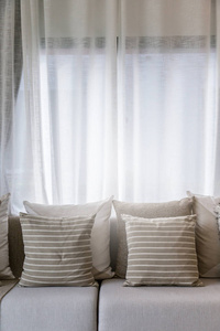 在阳光明媚的日子里，客厅的当代内部有部分沙发和白色窗帘的内部背景概念