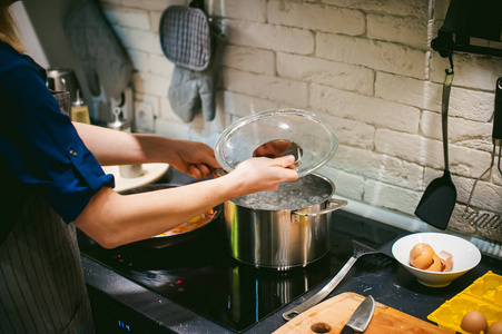 s hand dipped spaghetti in boiling water for cooking