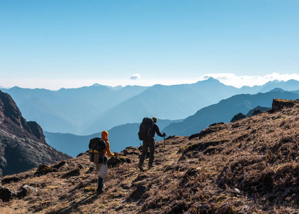 背着背包走在山中草脚后跟上的两个徒步旅行