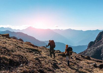 背着背包走在山中草脚后跟上的两个徒步旅行