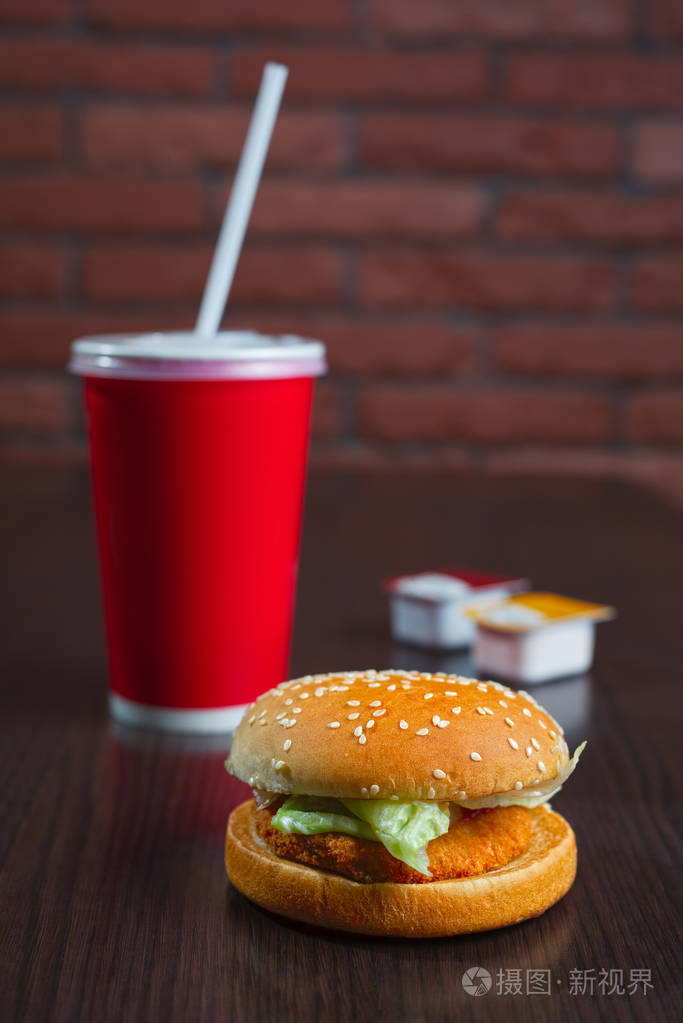 汉堡和纸杯可乐或果汁与金砖四国木制的桌子上