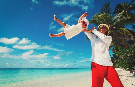 父亲和小女儿在热带海滩玩