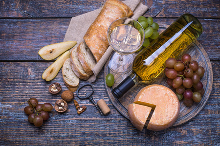 白红酒一瓶 软木 瓶螺杆和一套产品奶酪 葡萄 坚果 橄榄 无花果上一块木板，在背景