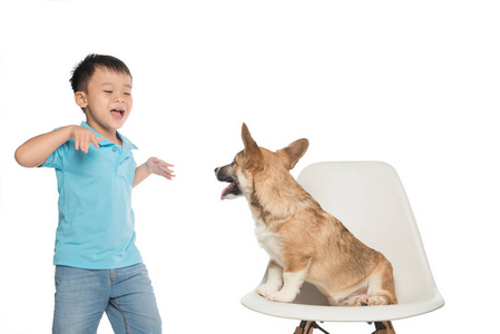 孩子小男孩和小彭布罗克威尔士矮脚狗的狗玩