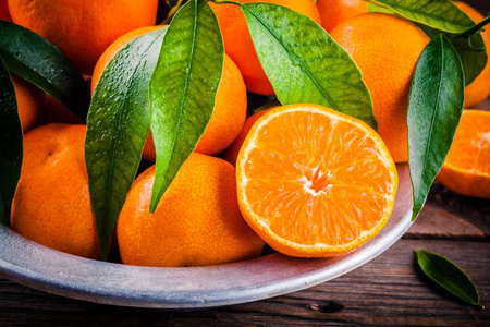 多汁的橘子有叶子在一个碗里的木制背景