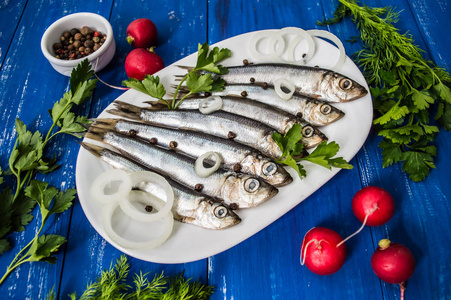 油性鲱鱼鲱鱼鱼与绿党在木制的蓝色背景.顶视图.特写照片