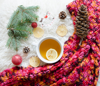 顶视图的红色针织的围巾和杯加柠檬的茶。冬天的心情。平躺的圣诞装饰