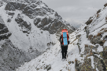 登山者在陡的雪覆盖在山上的悬崖和深渊背景在边坡上行走。风险和冒险室外的概念