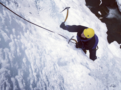 攀冰。男子攀爬的冰冻的瀑布