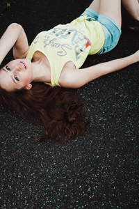 美丽的年轻时髦的女孩躺在沥青路面