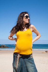 黄色衬衫孕妇在海滩
