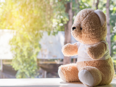 玩具熊坐在窗户旁边.孤独和等待概念照片