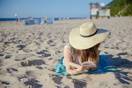 一个年轻黑发放松在沙滩上，读一本书的肖像