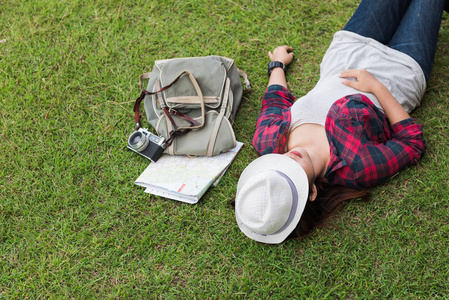 时髦女人的旅客躺在草地上