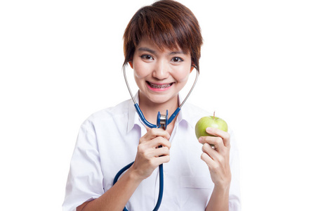 年轻的亚洲女医生用听诊器听一个苹果