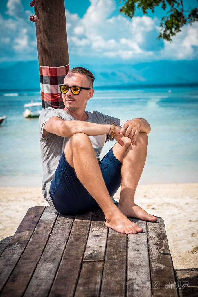 有魅力白种人的年轻人带着太阳眼镜构成对热带海滩的努沙蓝梦印度尼
