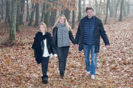 在秋天的家庭漫步在森林公园