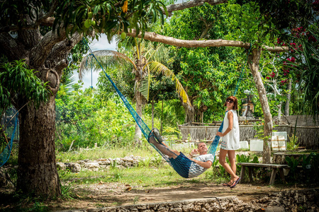 肖像的吊床上热带度假期间幸福浪漫情人岛巴厘岛，印度尼西亚。爱情场景。亚洲。女孩临近她的男朋友