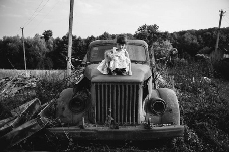 小女孩坐在一辆带娃娃的旧车