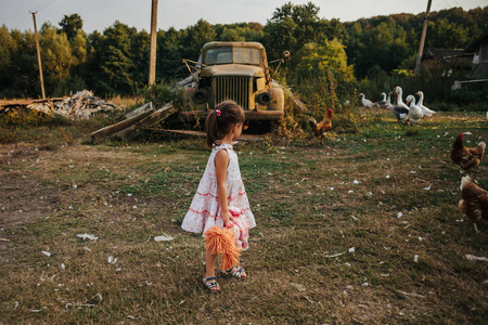 一个小女孩站在一辆带娃娃的旧车