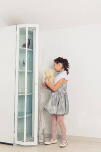 可爱的小女孩抱着一只泰迪熊。可爱的小宝宝在家里白色的房间里