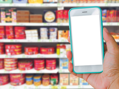 右手握着绿色的空白屏幕手机超市与模糊背景，在线购物的概念