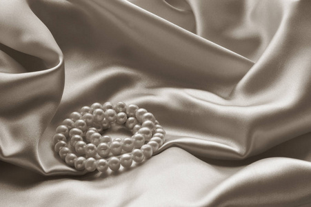 珍珠首饰披着米色真丝织物的细节