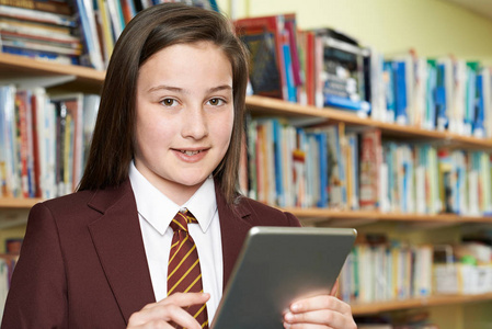 女孩穿着校服在库中使用数字平板电脑