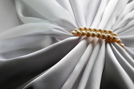 优雅的白色背景用丝绸和珍珠。美丽的丝绸窗帘