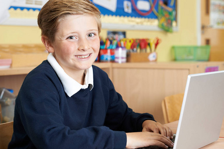 男小学生在计算机课上使用笔记本电脑