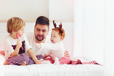 快乐的父亲和孩子们在圣诞节早上在家玩