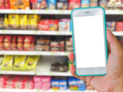 右手握着绿色的空白屏幕手机超市与模糊背景，在线购物的概念