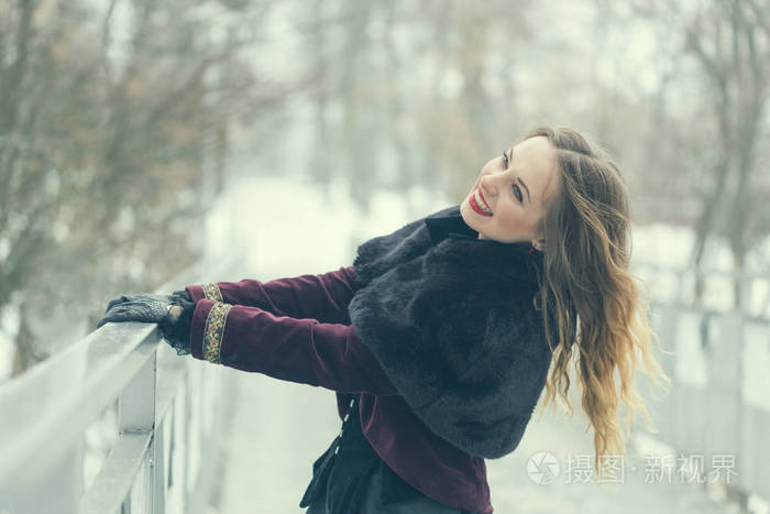 漂亮的女孩站在人行天桥上，在冬季