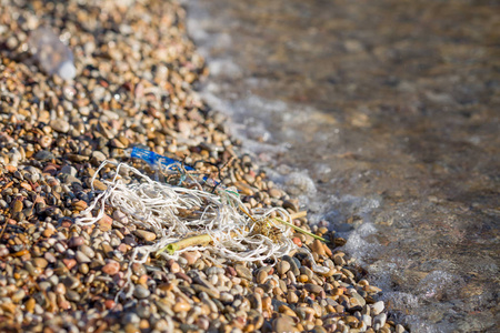 在鹅卵石海滩上, 用塑料污染的海滨