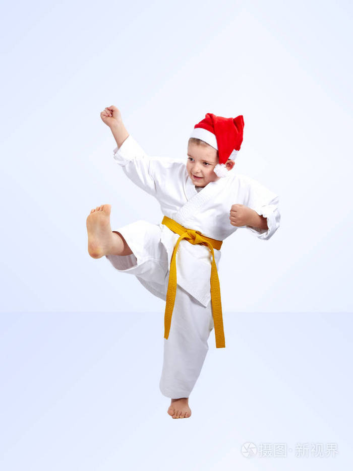 男孩的运动员跳动一脚踢在圣诞老人的帽子