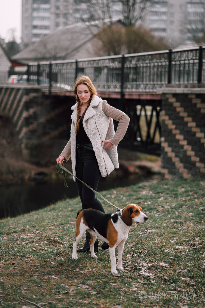 年轻的时髦女孩与她的宠物爱沙尼亚猎犬狗玩开心户外公园里