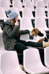 年轻的时髦女孩与她的宠物爱沙尼亚猎犬狗玩，俊平和拥抱和室外在玩老体育场