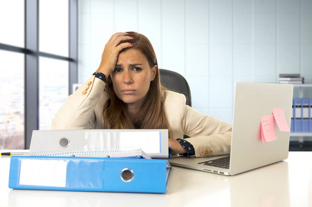 悲哀和绝望的女商人遭受压力和头痛在办公室膝上型电脑桌