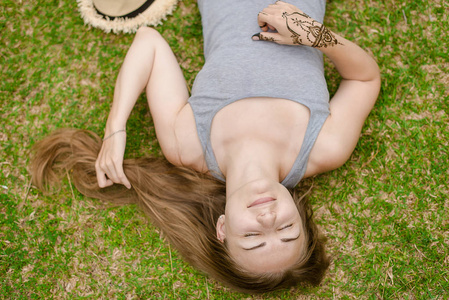 留着长头发的金发女孩躺在绿色草地上